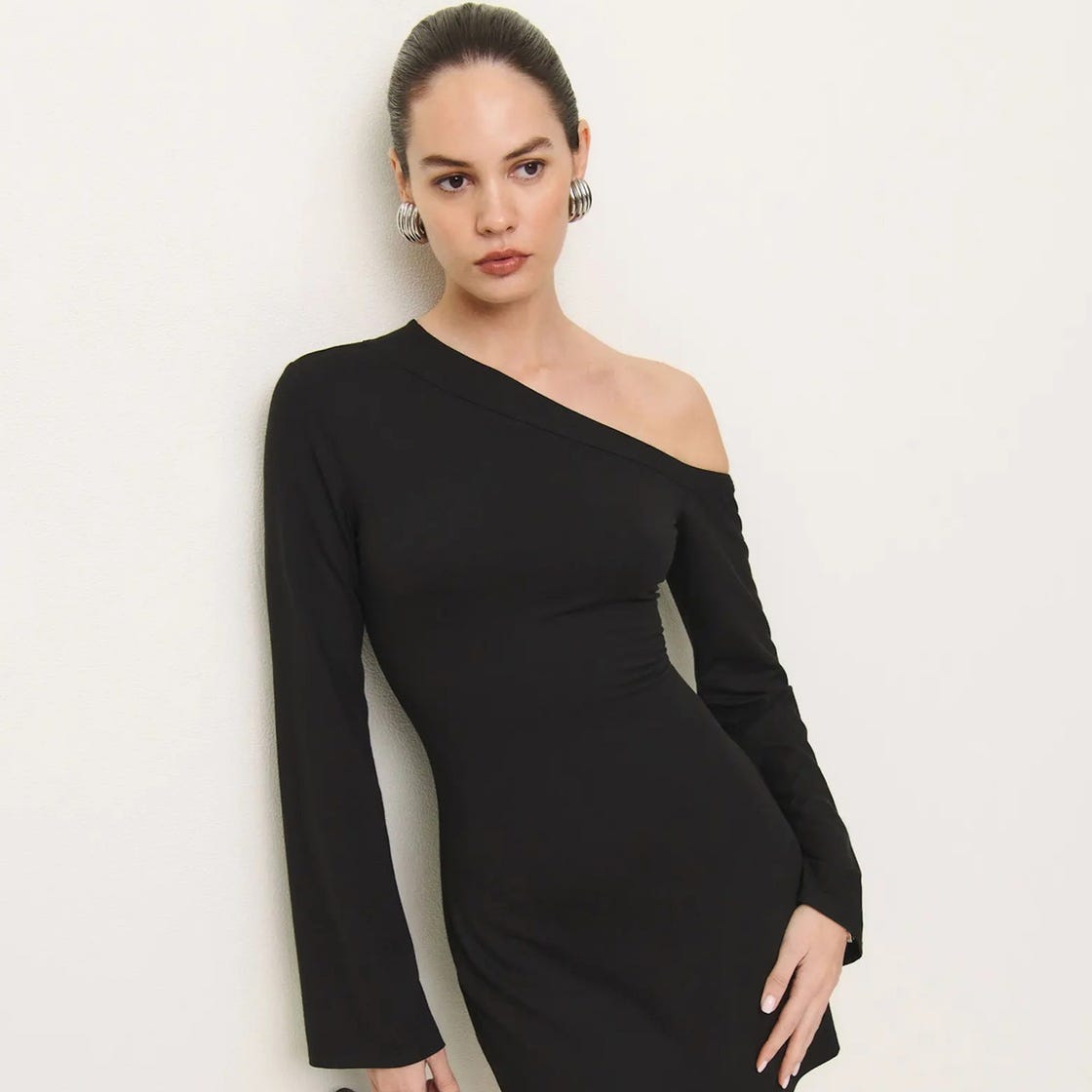 female model wearing a black asymmetrical dress with long sleeves