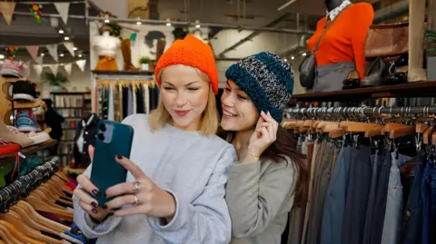 Getty Images Two young women taking selfies in a vintage clothes store
