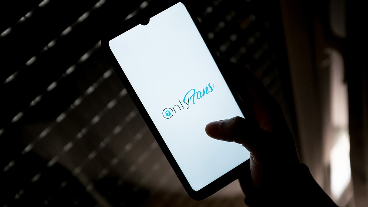 Someone holding a phone that shows the OnlyFans logo.