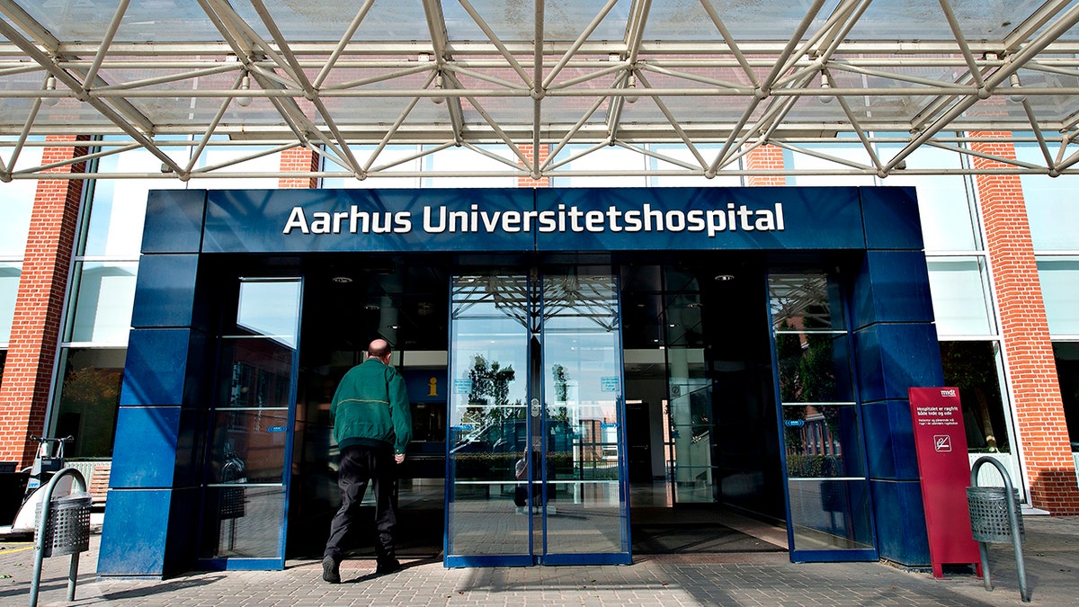 Man seen from behind as he walks toward entrance of Aarhus University Hospital in Aarhus, Denmark.