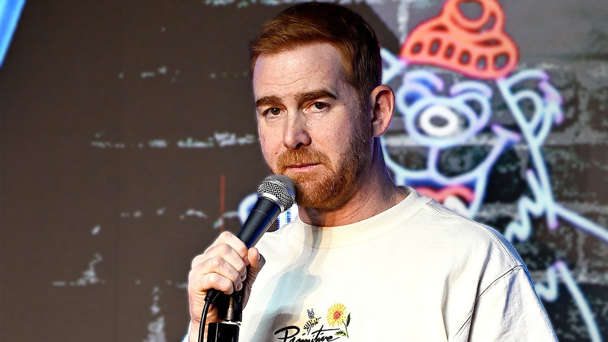 Comedian Andrew Santino holds a microphone