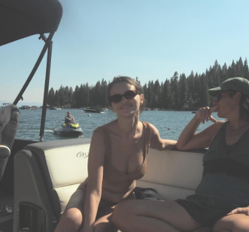 two individuals sitting on a boat with a lake view enjoying a sunny day