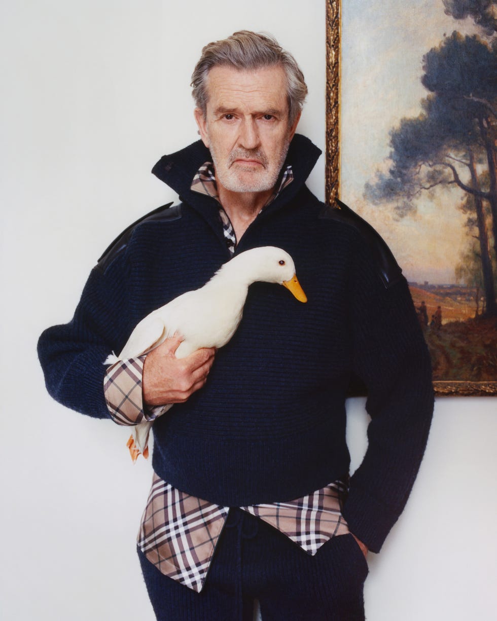 a person holding a duck dressed in a casual sweater and plaid shirt