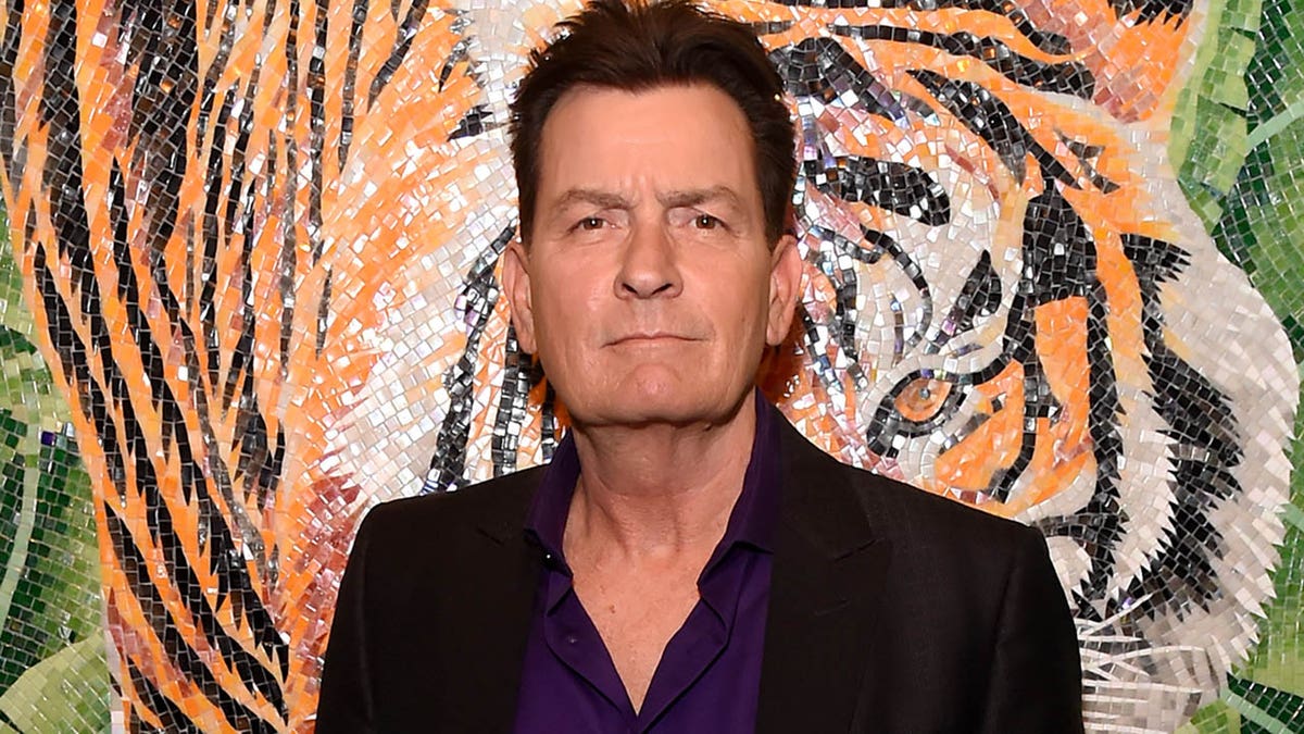 charlie sheen poses in front of tile tiger mural
