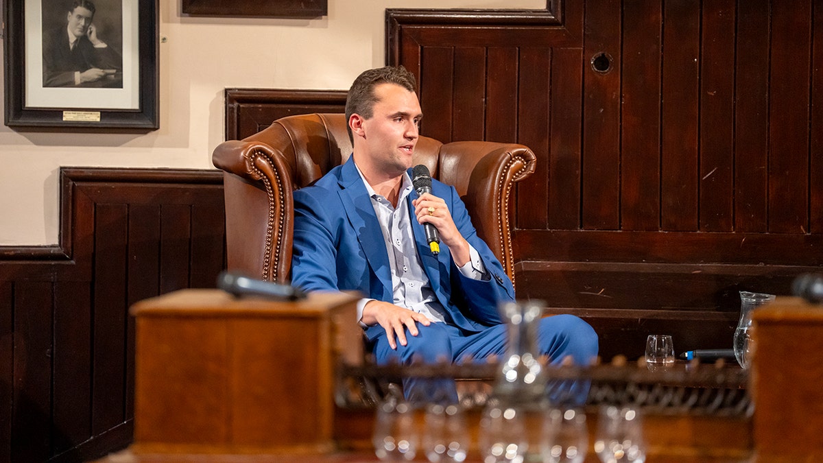 Charlie Kirk holds a microphone during a speaking event in Cambridge.