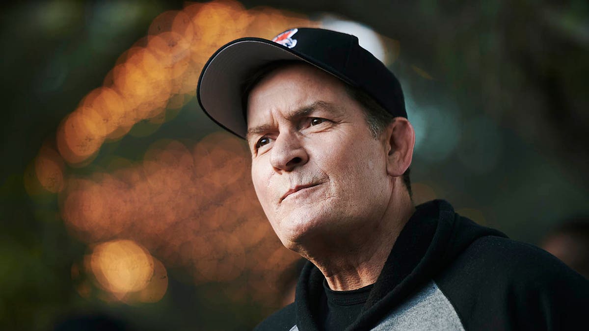 A close-up of Charlie Sheen wearing a baseball hat. 