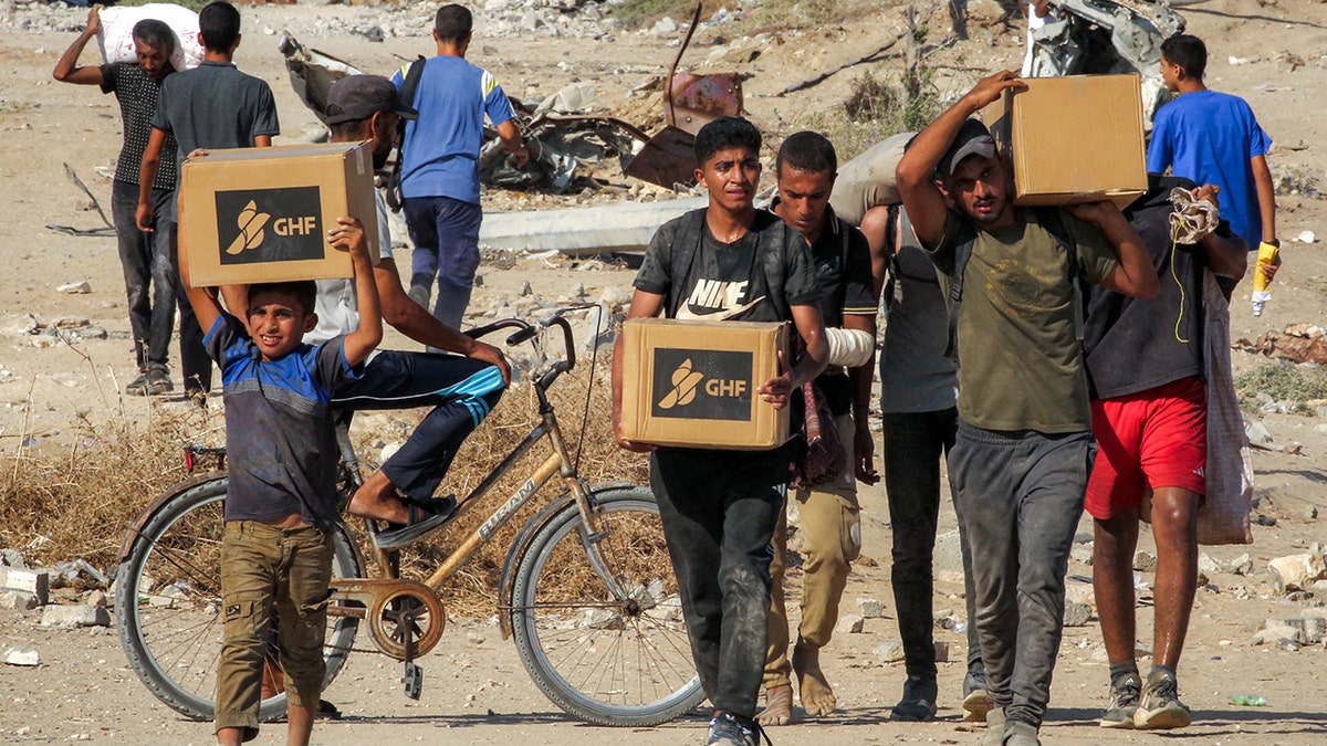 Gazans walk with boxes of humanitarian aid they received at a distribution centre run by the U.S. and Israeli-backed Gaza Humanitarian Foundation (GHF).
