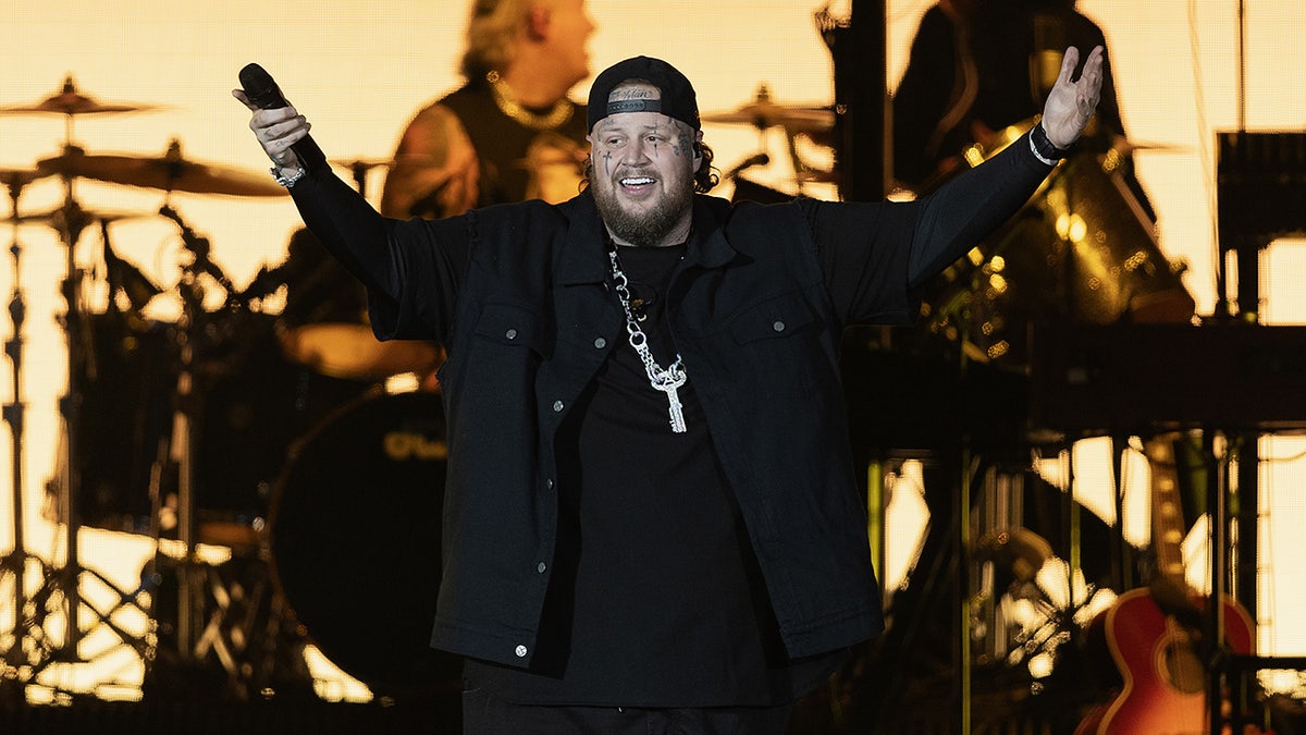 Jelly Roll on stage holding up both arms