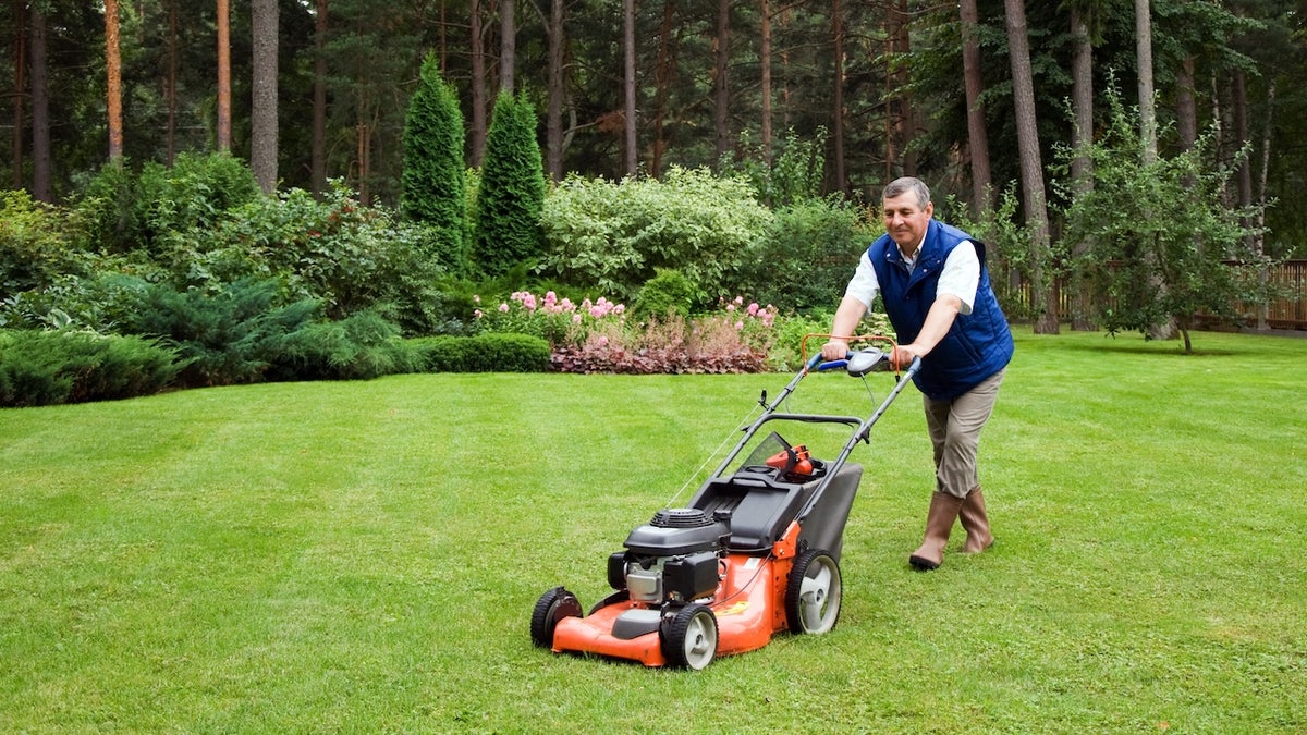 man pushing a lawnmower around lawn