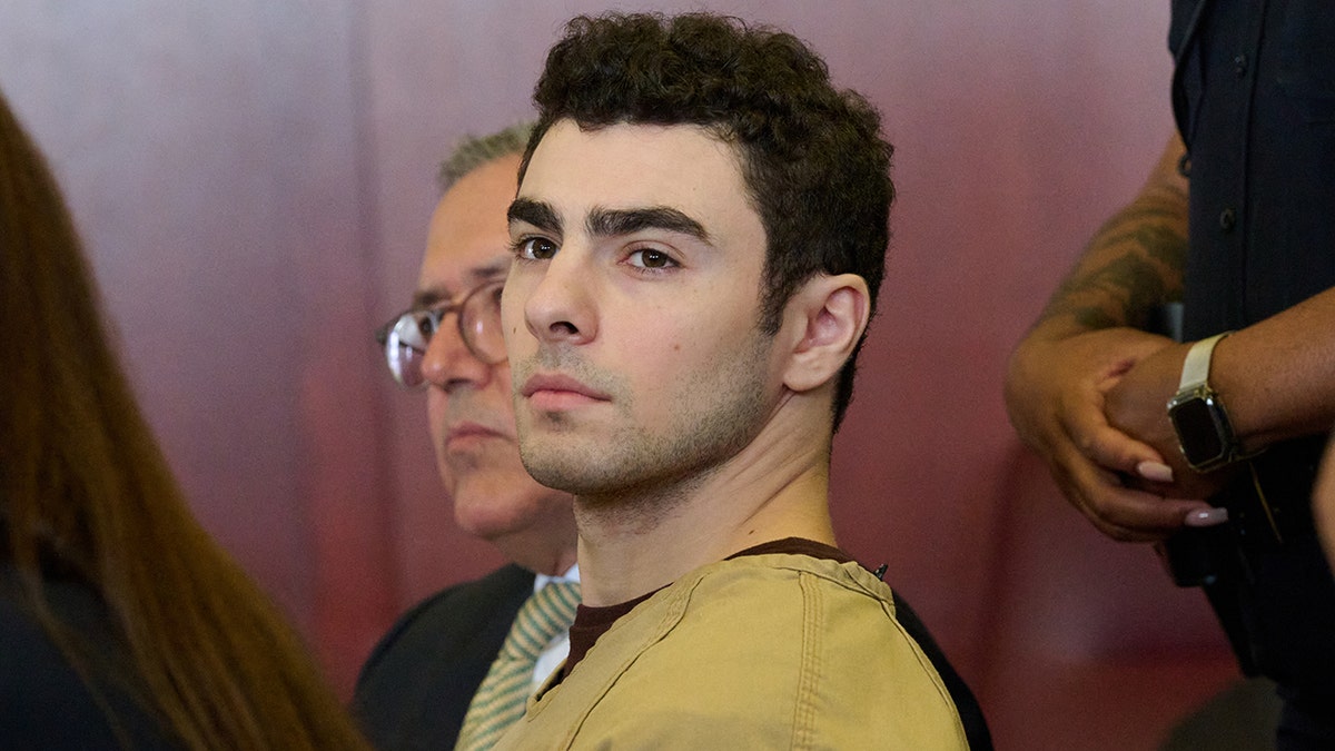 Luigi Mangione seated in court as judge drops terrorism charges.