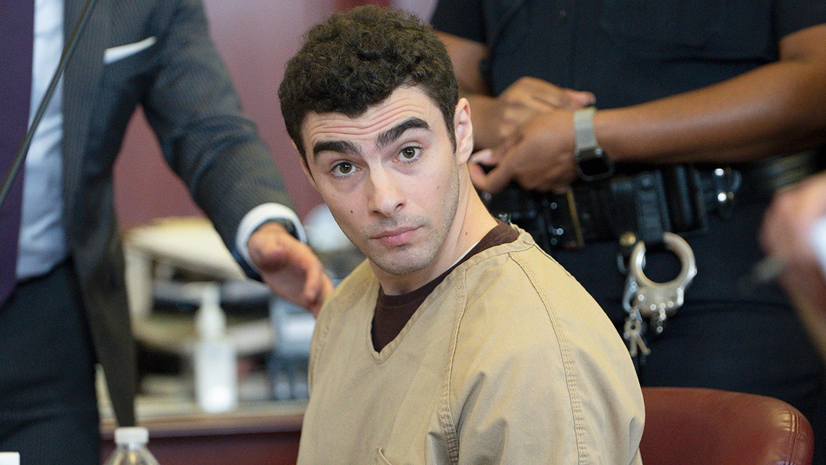 Luigi Mangione seated in court as judge drops terrorism charges.