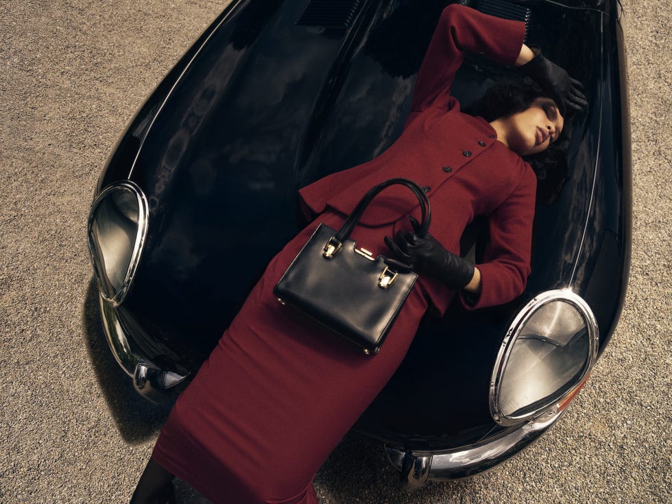 a stylish figure reclining on a vintage black sports car