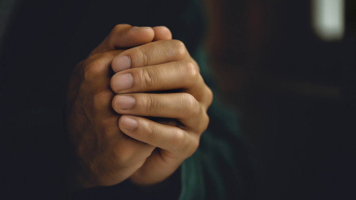 prayer hands in dark background