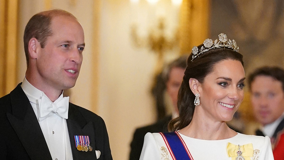 A close-up of Prince William in Kate Middleton in formal wear inside Buckingham Palace.