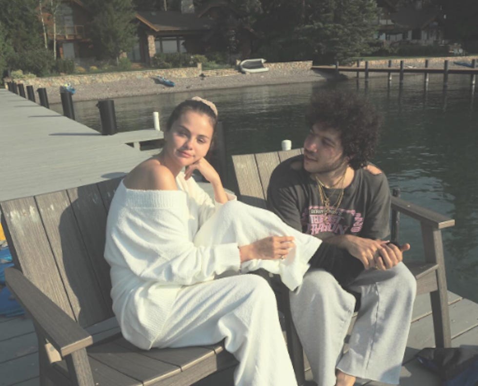 two people sitting on a dock by a lake