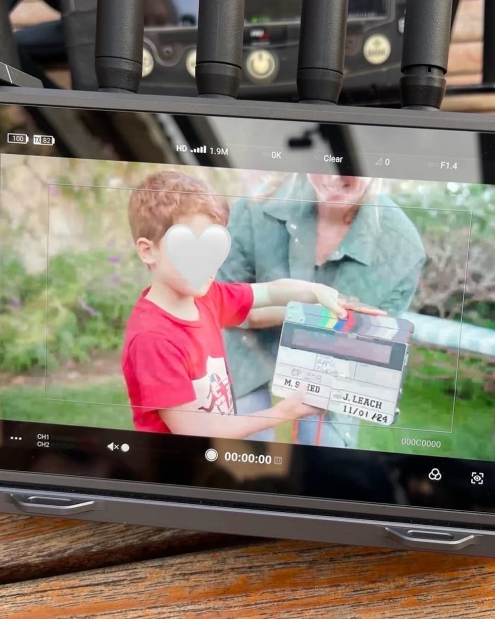clapperboard being held by a child in front of a camera monitor