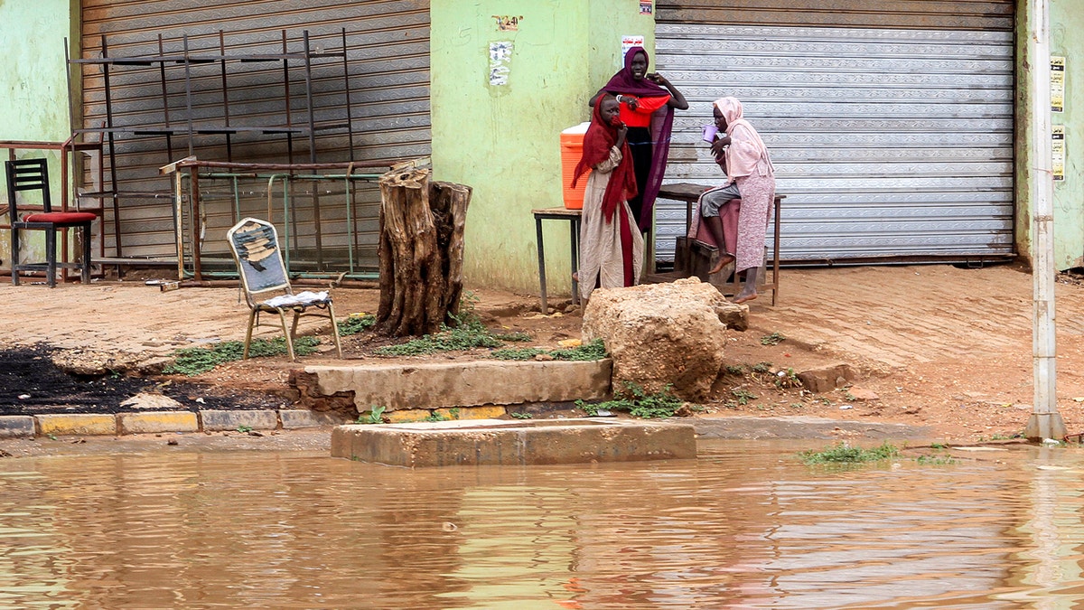 Women gather along the side of a flooded street