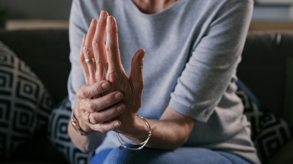 A woman clutching her hand to show arthritis pain
