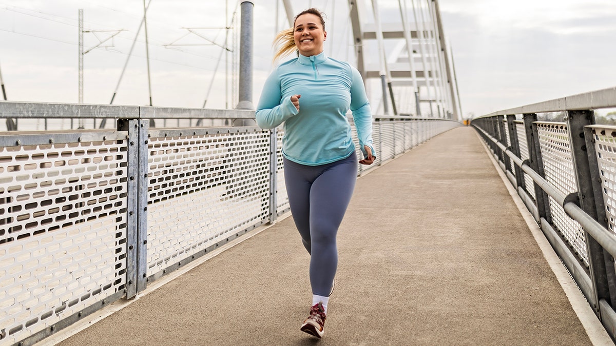 A slightly overweight young woman goes for jog on a bridge