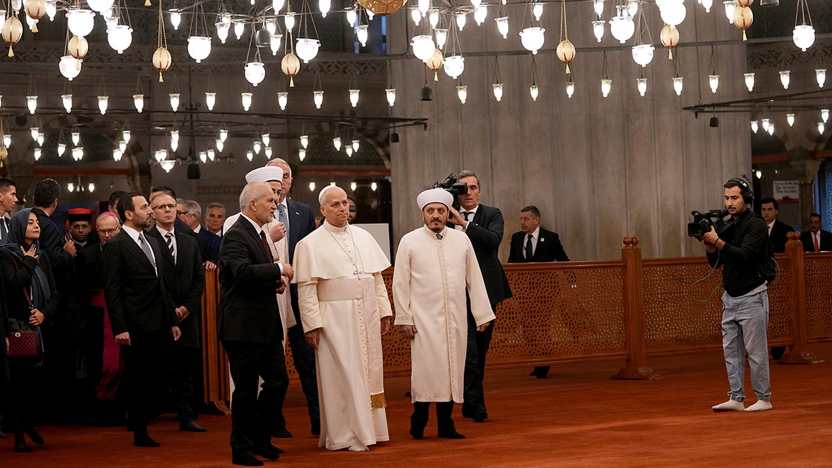 Pope Leo XIV, center, walking with Muezzin Musa Asgın Tunca, left, Dr. Emrullah Tuncel, second from left, and Imam of Mosque Sultanahmet Fatih Kaya, inside the illuminated Sultan Ahmed Mosque in Istanbul.