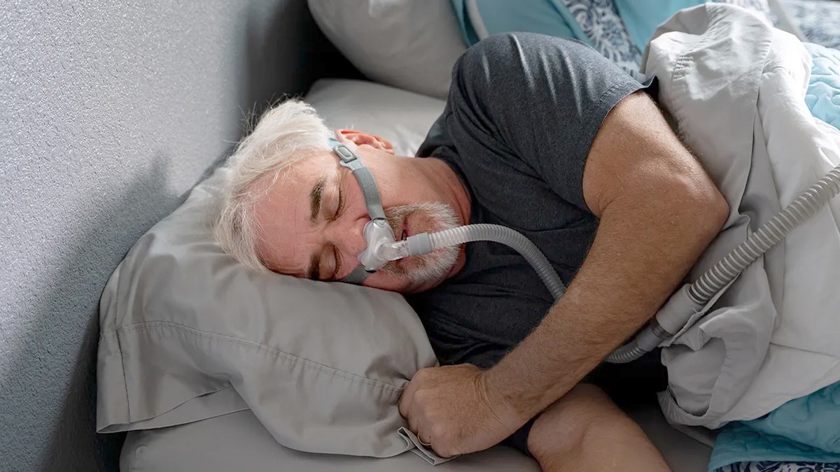 Man with CPAP mask sleeps on his side.
