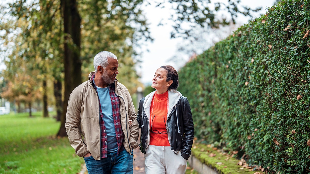 Couple walking together outdoors looking at each other and smiling