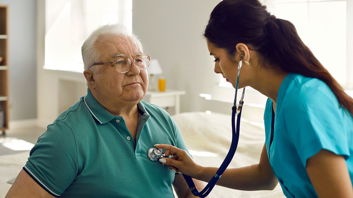 Woman doctor checks older man's heart rate with a stethoscope